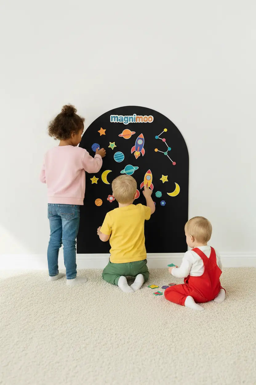 Kids playing with space-themed magnets on a black magnet board.
